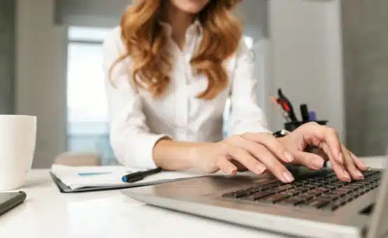 Femme tapant sur un clavier d'ordinateur, illustration d'un article sur c'est quoi le SEO.